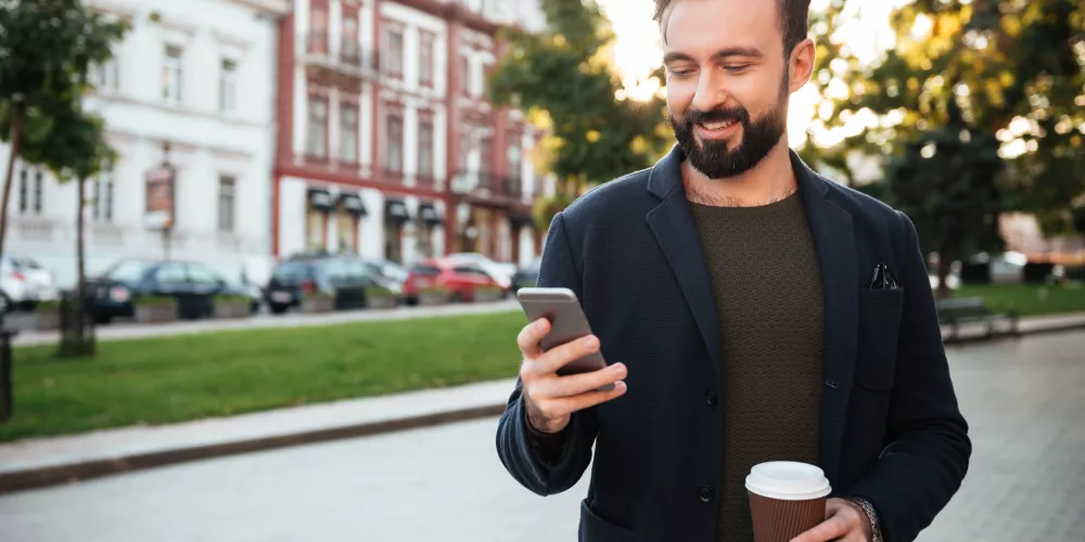 Homme marchant dans la rue un téléphone à la main