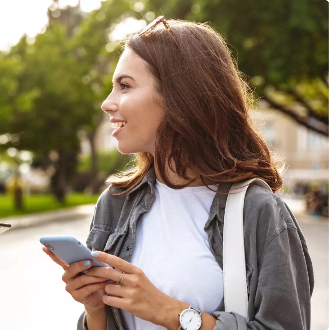 Jeune femme souriante dans la rue avec un téléphone à la main