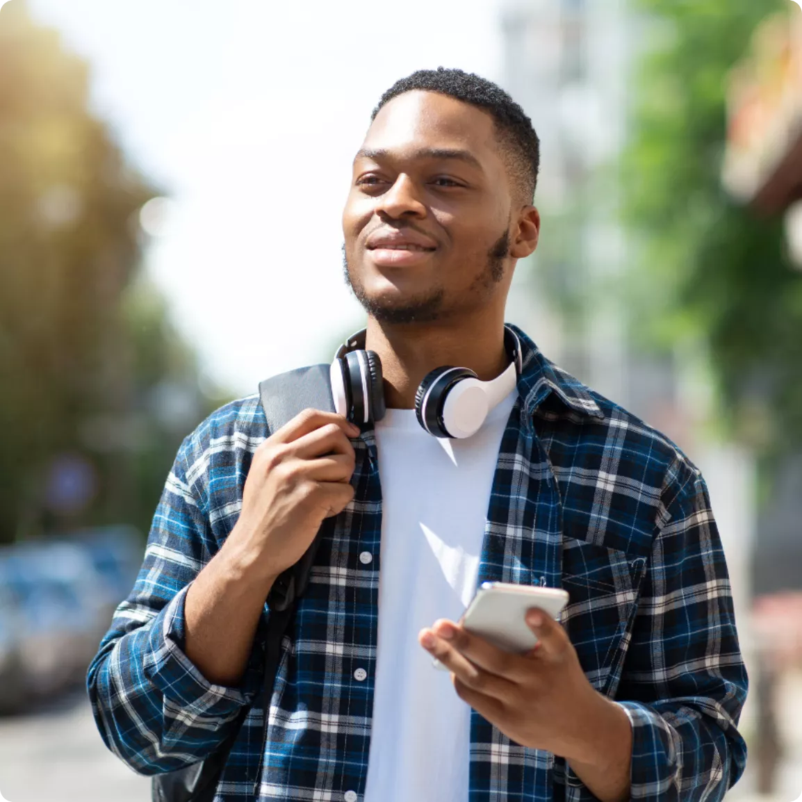 Homme souriant marchant dans la rue un téléphone à la main